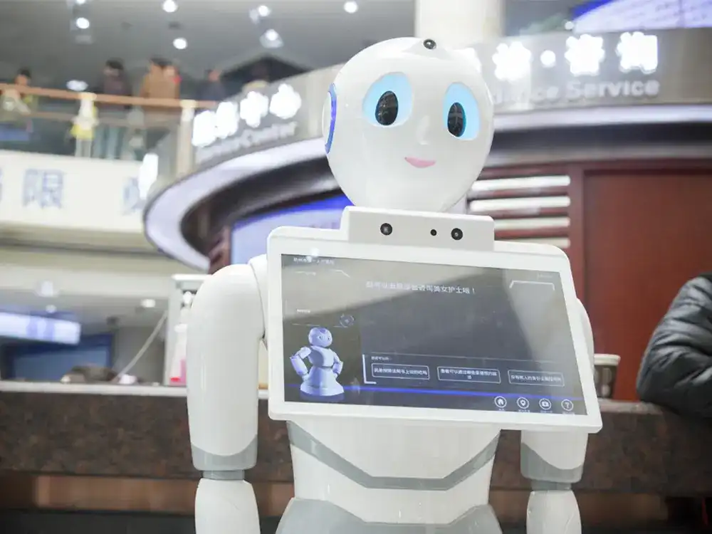 A humanoid medical service robot with a large touchscreen chest display standing in a hospital lobby, designed to provide patient guidance and information.