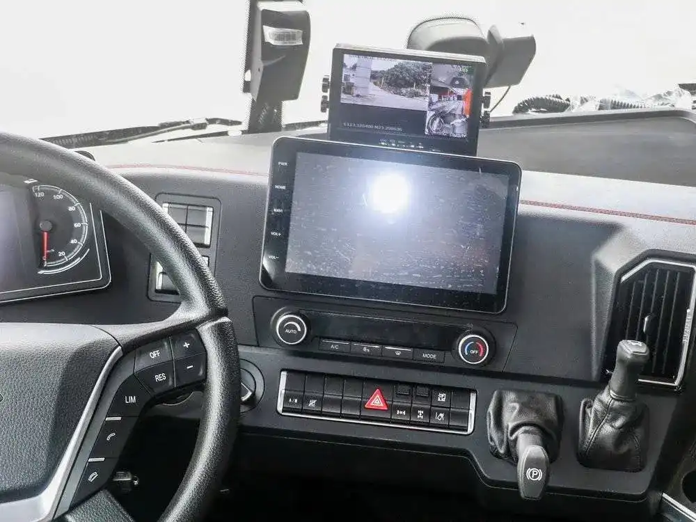 The interior dashboard of a modern vehicle featuring a large central touchscreen and a secondary monitor showing real-time external camera feeds for enhanced road safety.