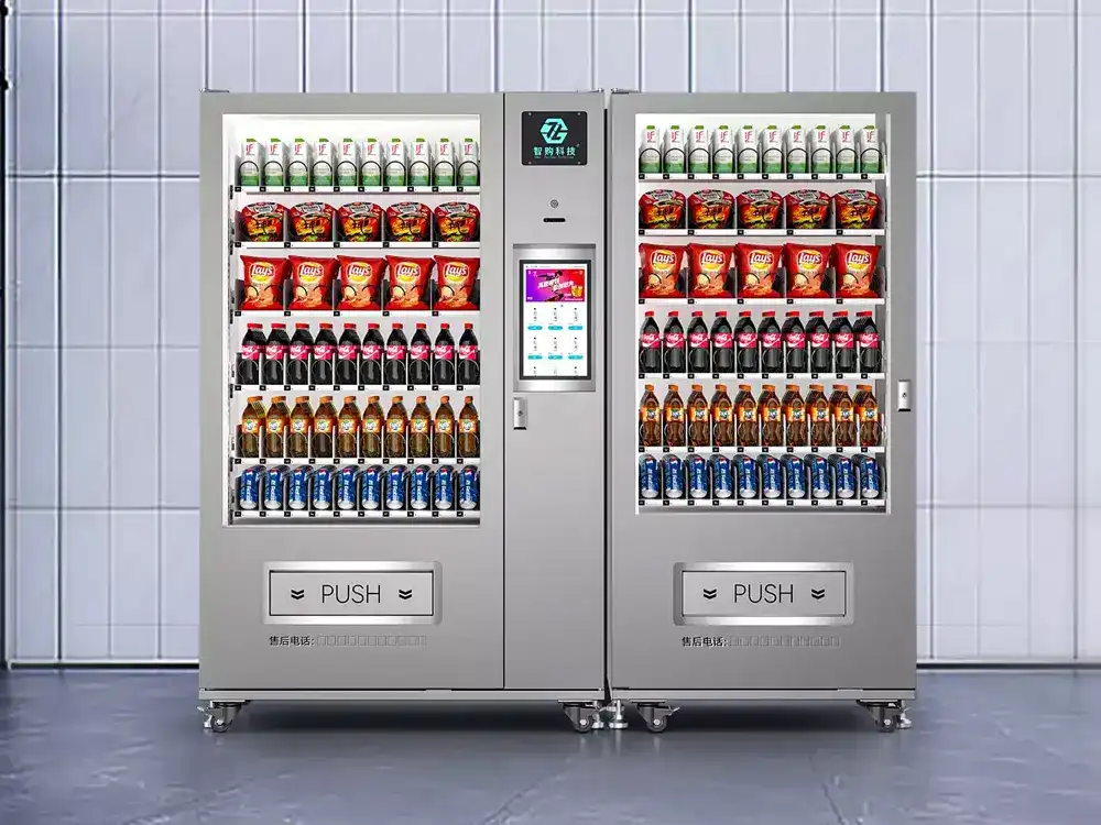 A large, dual-bay smart vending machine with a central touchscreen interface, stocked with a variety of snacks and beverages for automated commercial retail.