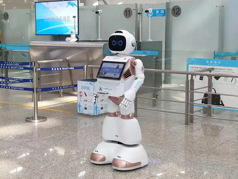 A sleek, white service robot with digital eyes and an interactive tablet, patrolling an airport terminal to assist travelers with flight information and wayfinding.