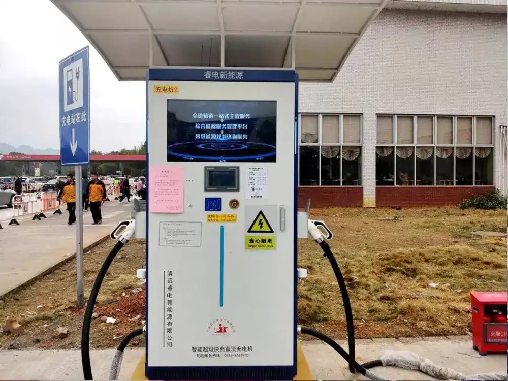 A heavy-duty outdoor electric vehicle fast-charging station with a large integrated advertising display, dual charging nozzles, and safety warning indicators.